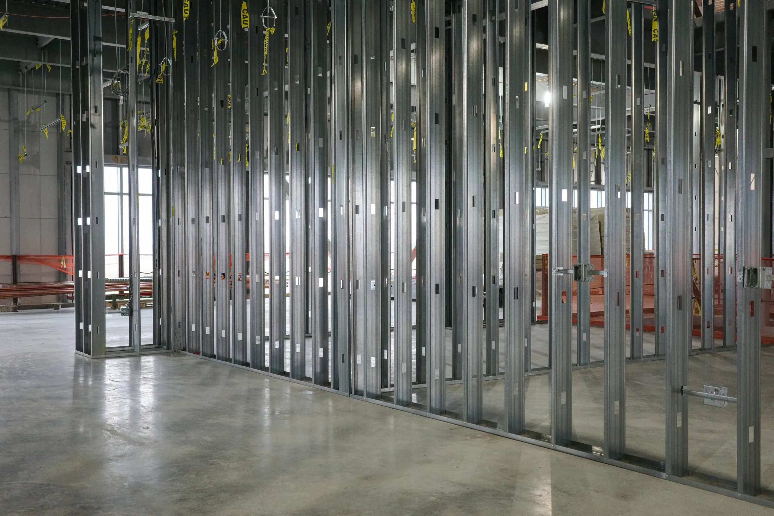 Light-gauge steel-stud partition framing erected in a commercial interior, studs and track in place before the drywall is hung